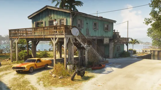 Casa sobre pilotes junto al agua con un coche aparcado delante.